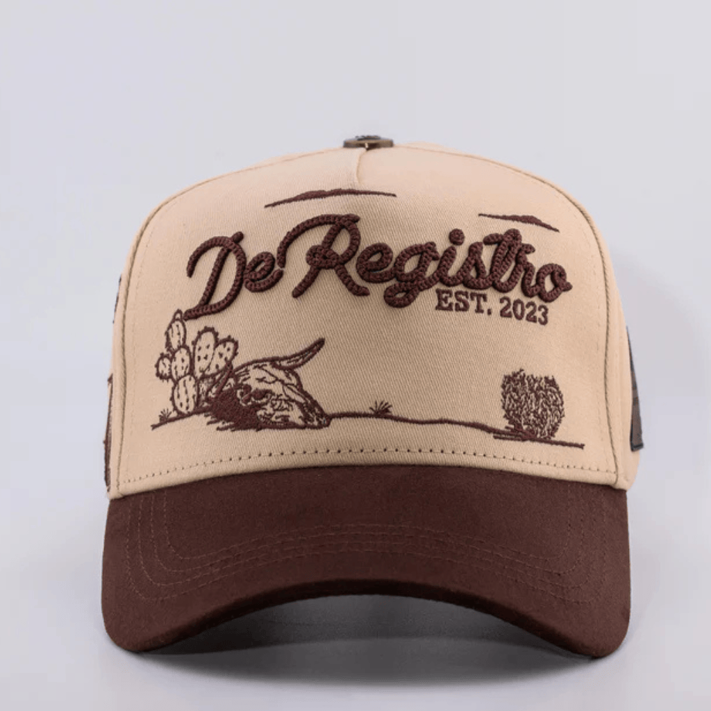 Gorra beige con visera café y bordado “De Registro EST. 2023”.