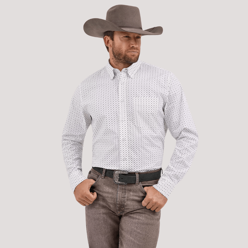 Hombre con sombrero y camisa blanca estampada, estilo western elegante.