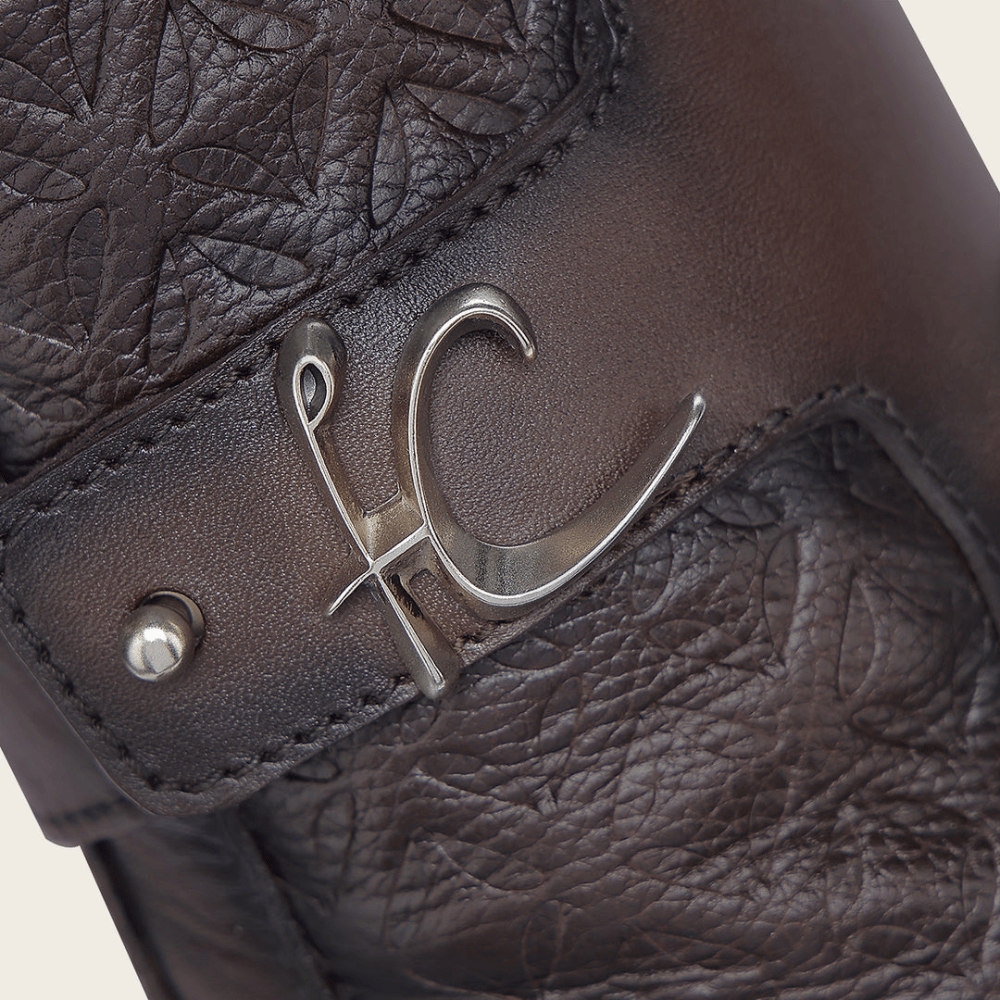 Primer plano del herraje metálico con el logo de Cuadra sobre la textura.