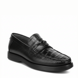 Loafer negro en piel de caimán con textura marcada y suela oscura.