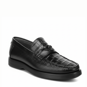 Loafer negro en piel de caimán con textura marcada y suela oscura.
