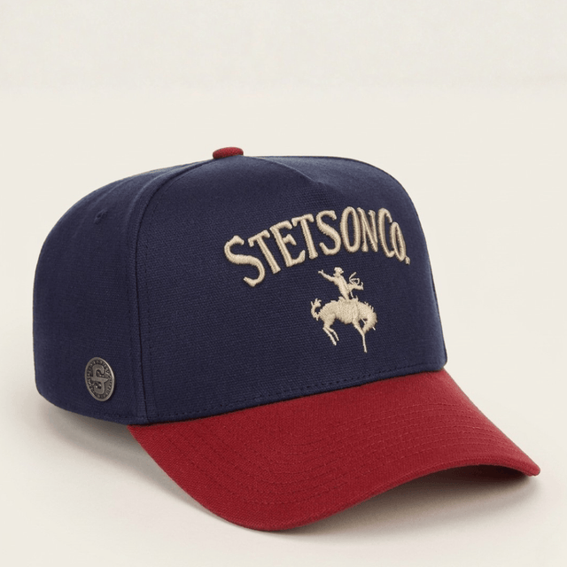 Gorra azul marino con visera roja y bordado frontal de jinete.