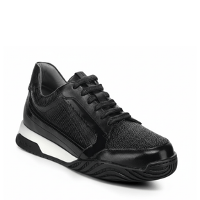 Tenis negro con paneles texturizados y suela deportiva bicolor.