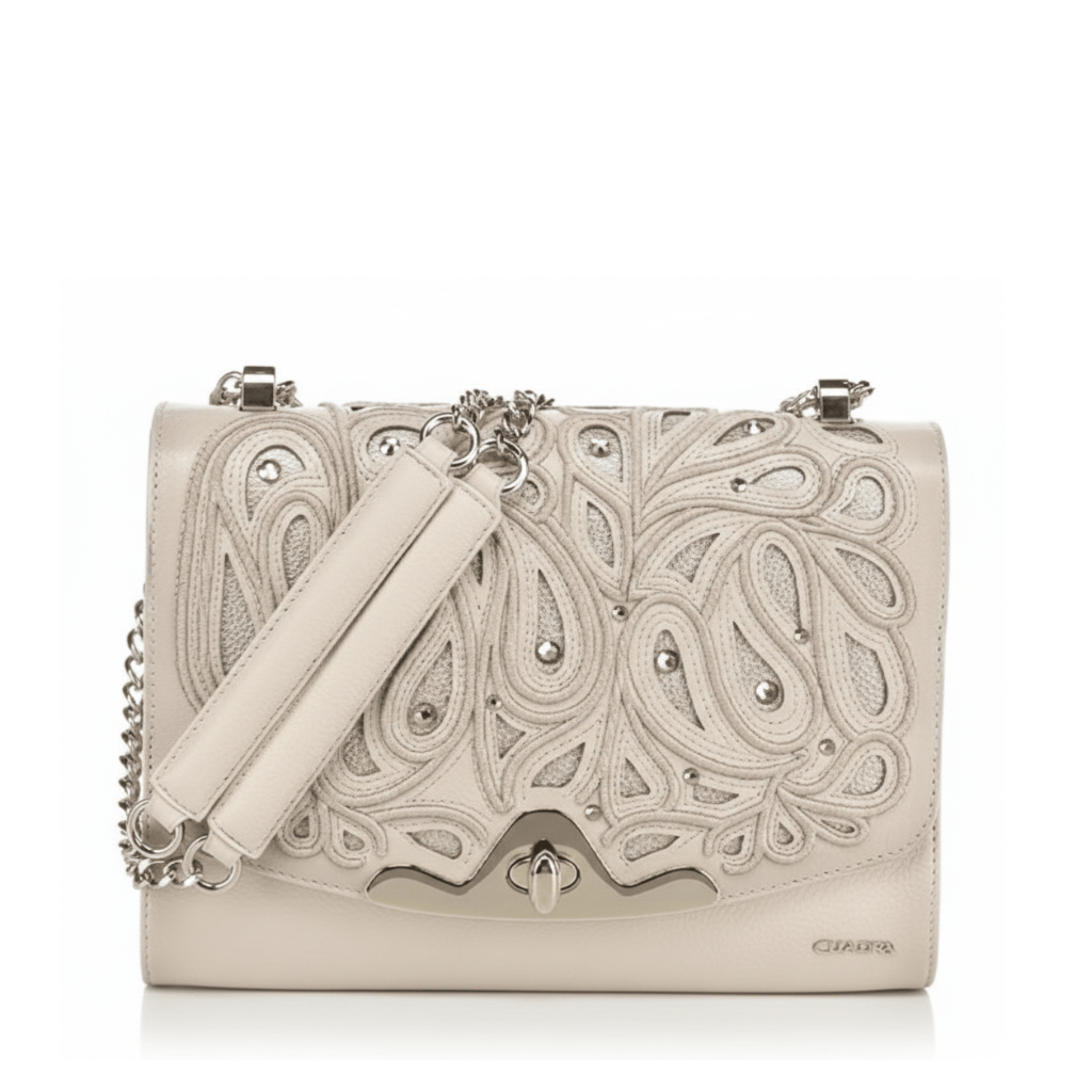 Bolso estructurado con diseño calado ornamental y herraje metálico frontal.