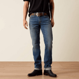 Vista frontal de jeans slim azul con botas negras y cinturón.