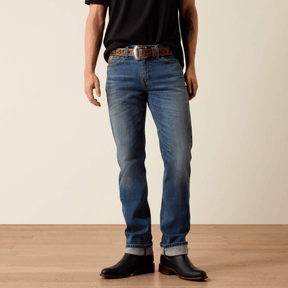 Vista frontal de jeans slim azul con botas negras y cinturón.