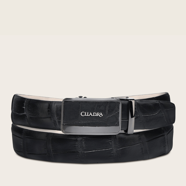 Cinto de piel exotica negra con hebilla metálica rectangular grabada.