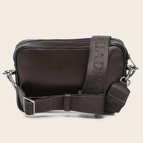 Parte trasera de la bandolera en piel lisa marrón, con correa ajustable de textil.