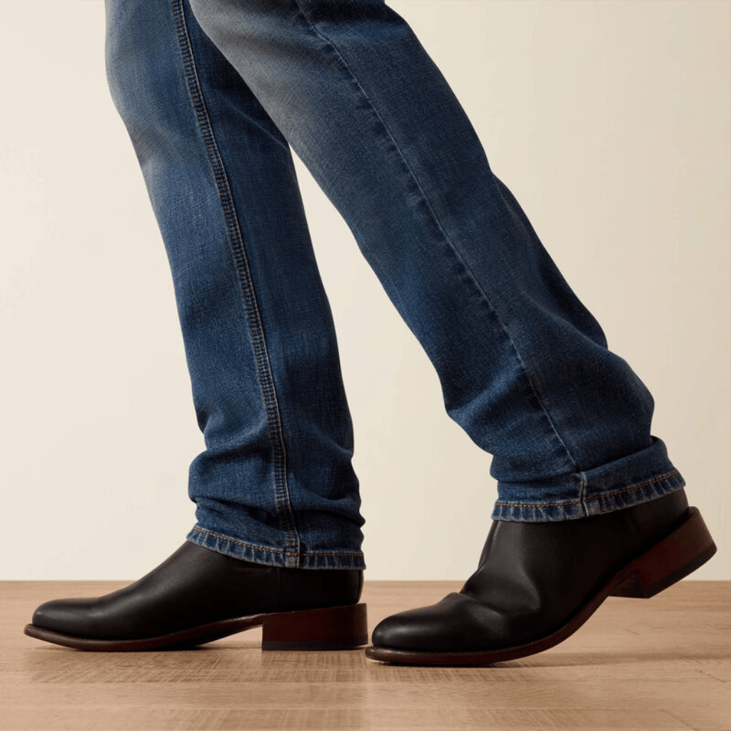 Detalle inferior del jean sobre botas negras.