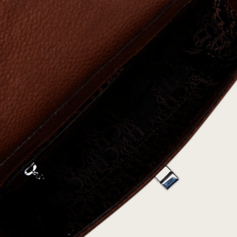 Interior del bolso con forro oscuro estampado y compartimento con cierre.