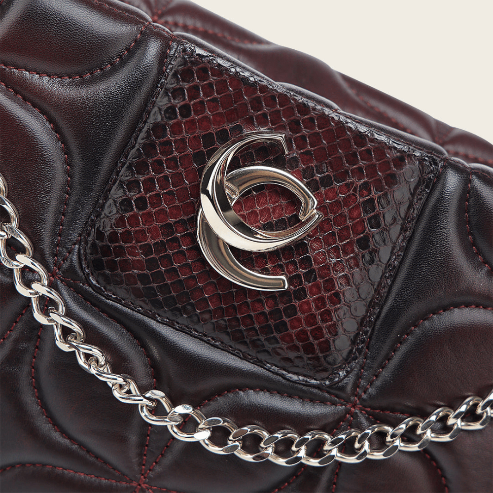 Detalle cercano del monograma metálico sobre piel de pitón.