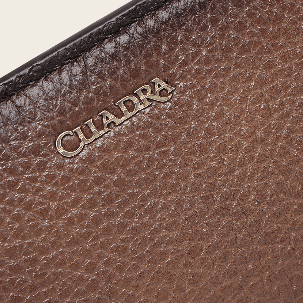 Detalle del logotipo Cuadra grabado en relieve sobre la textura del cuero.