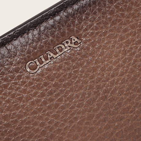 Detalle del logotipo Cuadra grabado en relieve sobre la textura del cuero.