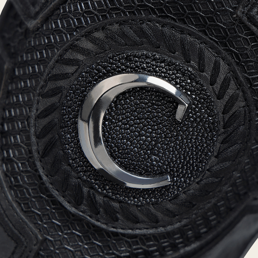 Primer plano del emblema metálico sobre tejido negro.